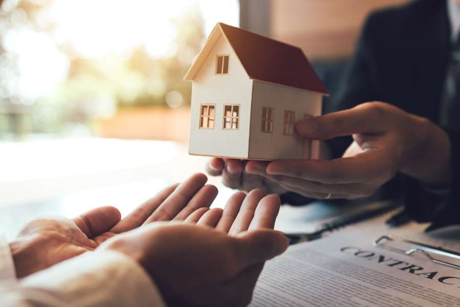 Remise symbolique d'une maquette de maison entre un agent et un client lors d'une transaction en immobilier industriel.